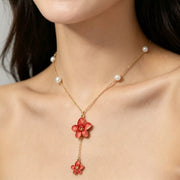 Close-up of gold-tone chain, pearl accents, and red flower pendant drops