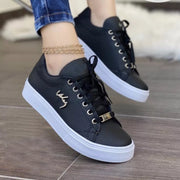 Black lace-up sneakers with perforated panels and white soles worn with jeans