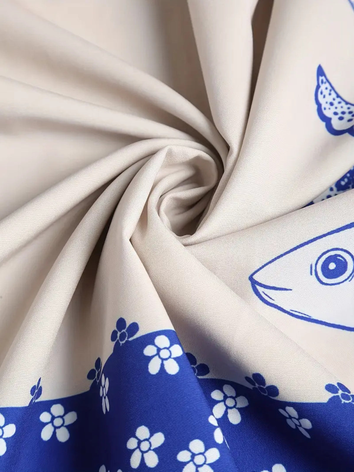 White dress fabric twisted to show blue sardine motifs and the dark blue floral border.