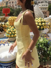 Side view showing the yellow gingham dress's fitted shape and shoulder bow ties.