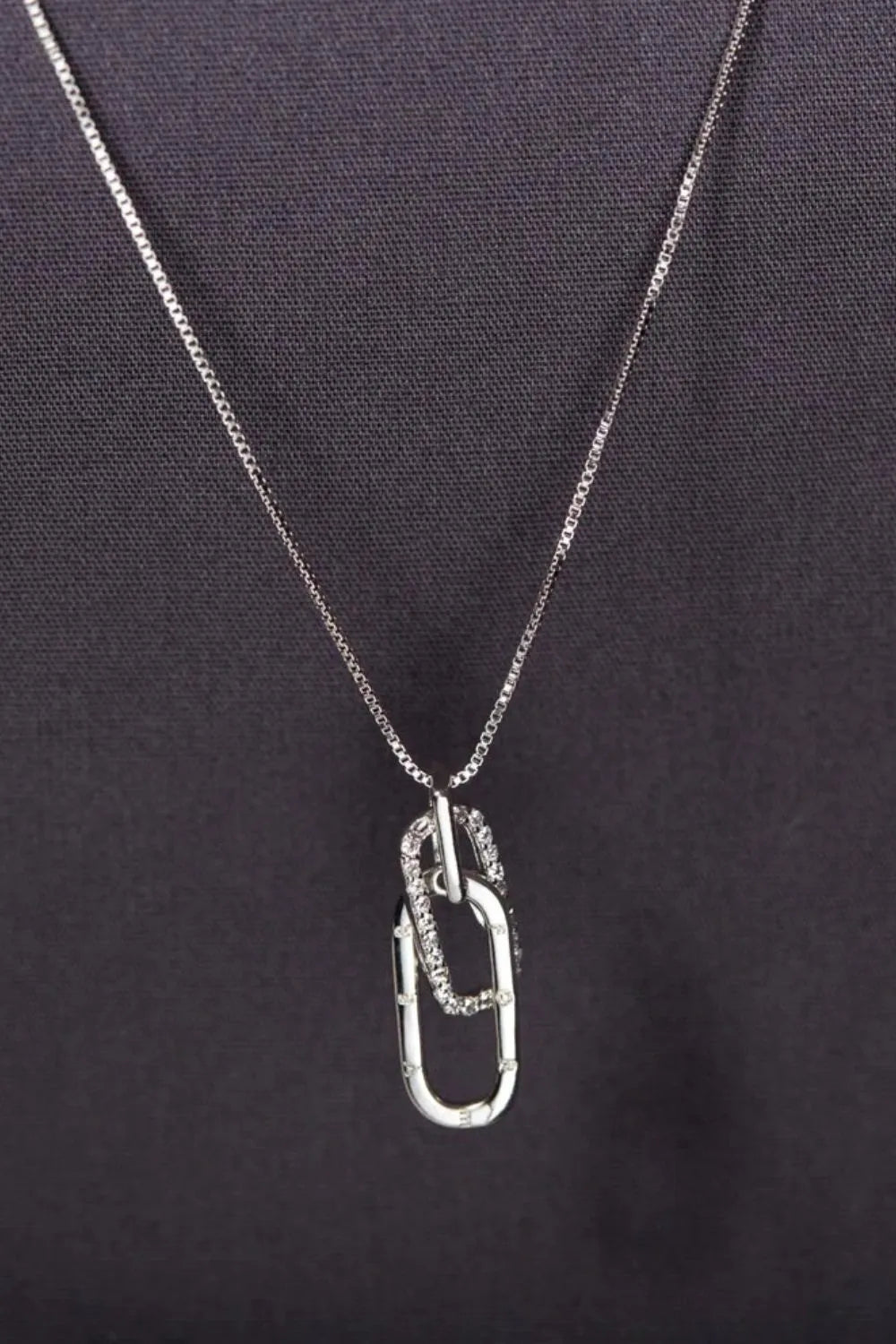 Silver-tone open rectangular pendant necklace on dark background