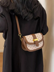 Cream and brown patterned crossbody bag shown from the side on a long shoulder strap