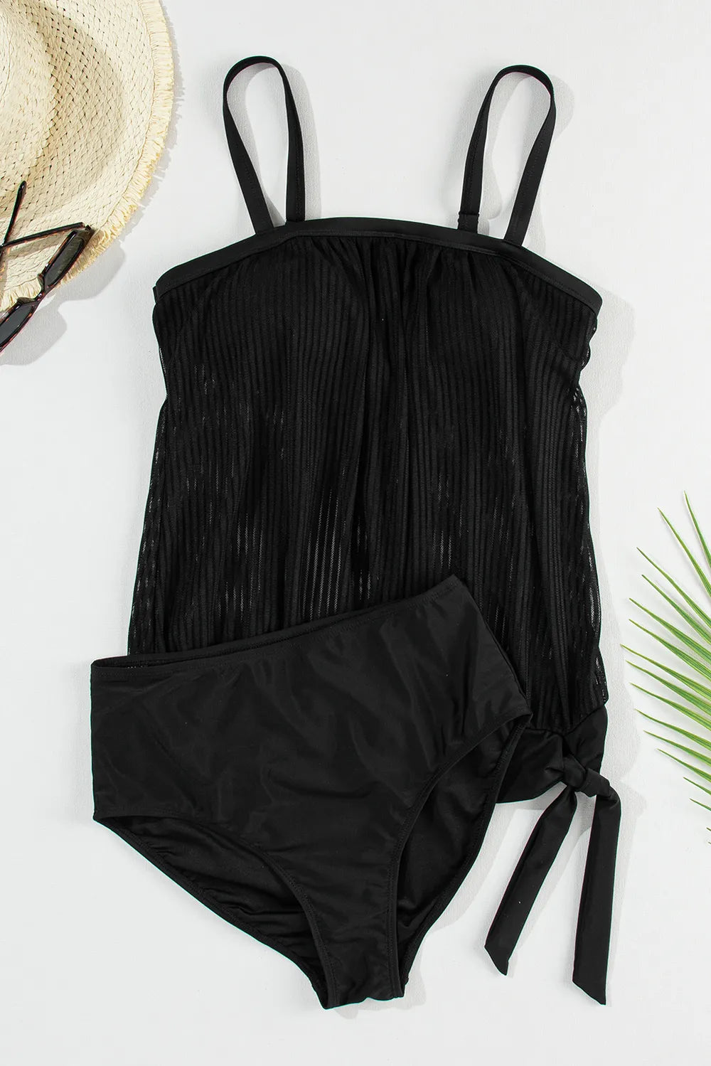 Black tankini top and briefs arranged flat, showing the pleated overlay and side tie.