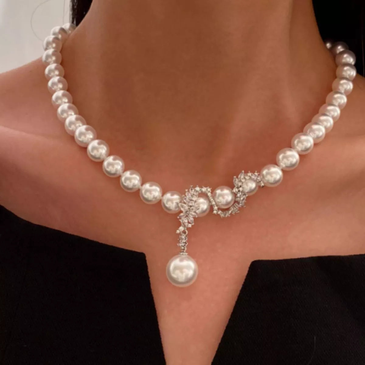 Front view of white pearl necklace with crystal floral center and pearl pendant