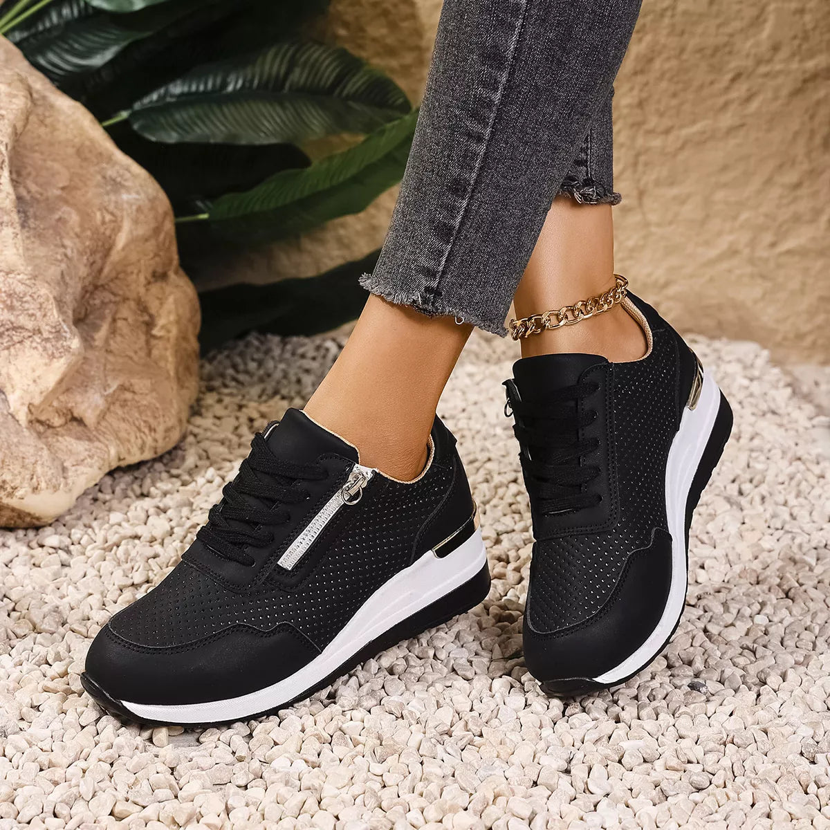 Black knit lace-up wedge sneakers worn with jeans beside rocks