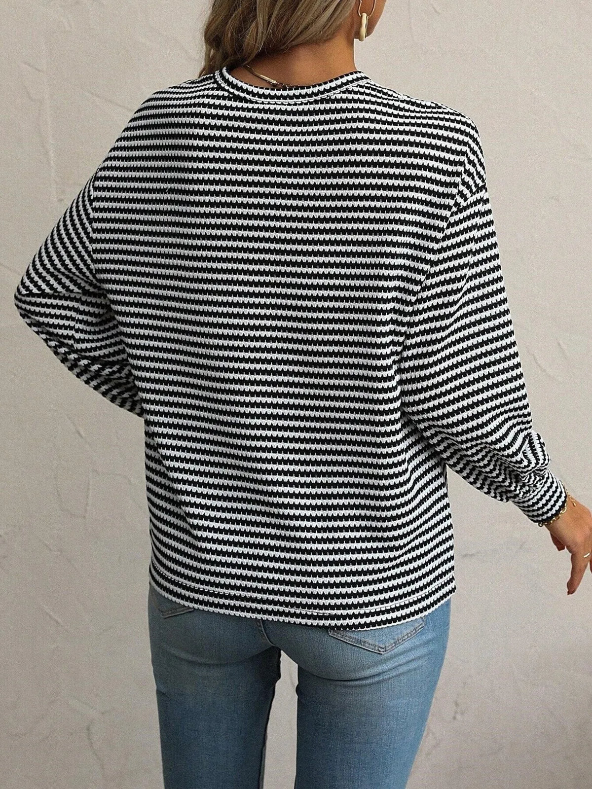 Rear view showing the long sleeves and hem of striped top