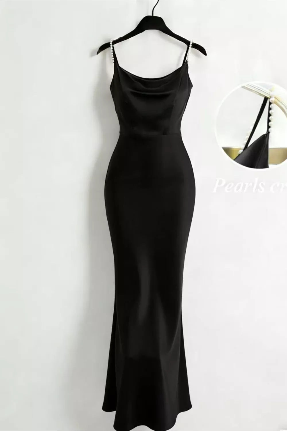 Black satin cowl-neck maxi dress with pearl straps displayed on a hanger.