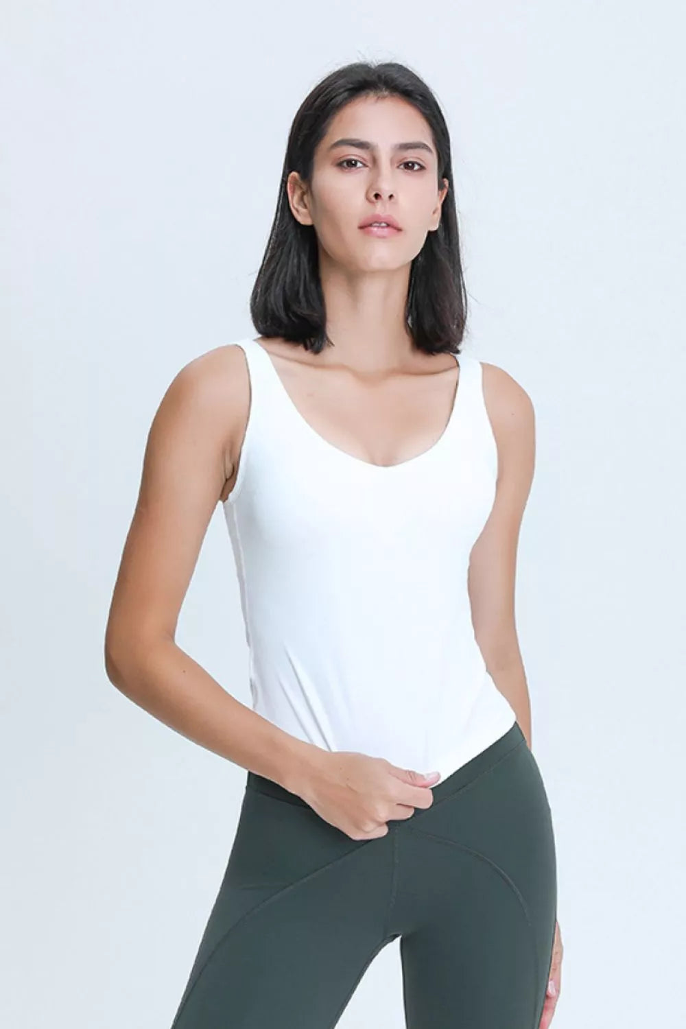 Front view of a woman wearing a white V-neck active tank top.