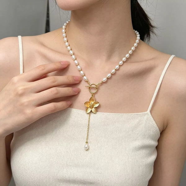 Pearl choker with gold flower pendant and drop, styled over a white top