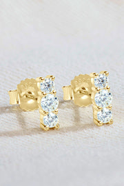 Pair of three-stone vertical moissanite studs on textured surface