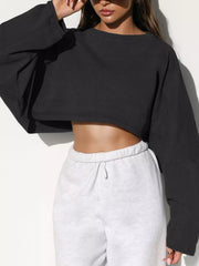 Front view of a black cropped sweatshirt with oversized sleeves, worn with light gray sweatpants.