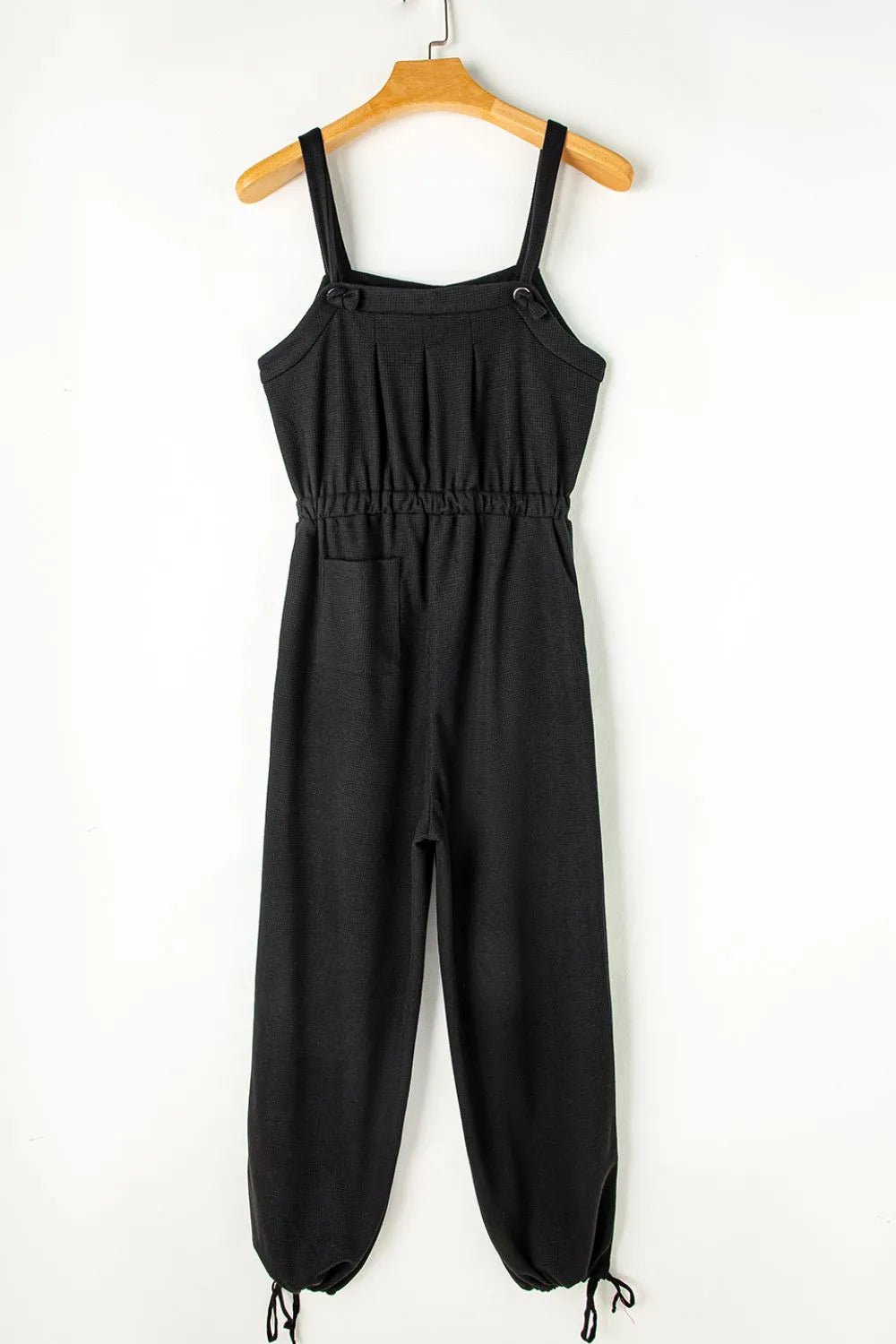 Black textured jumpsuit, back view on wooden hanger