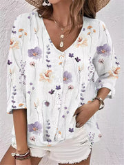 Model wearing white floral blouse with colorful flowers and white shorts.