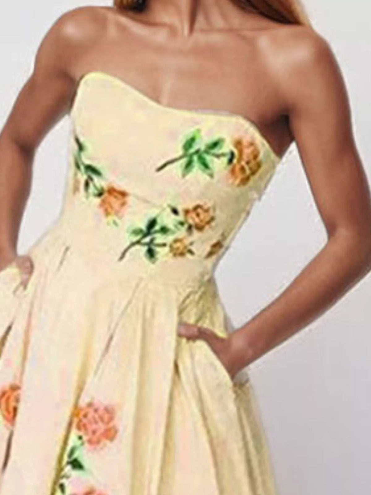 Close view of cream strapless dress bodice with colorful floral embroidery.
