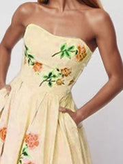Close view of cream strapless dress bodice with colorful floral embroidery.