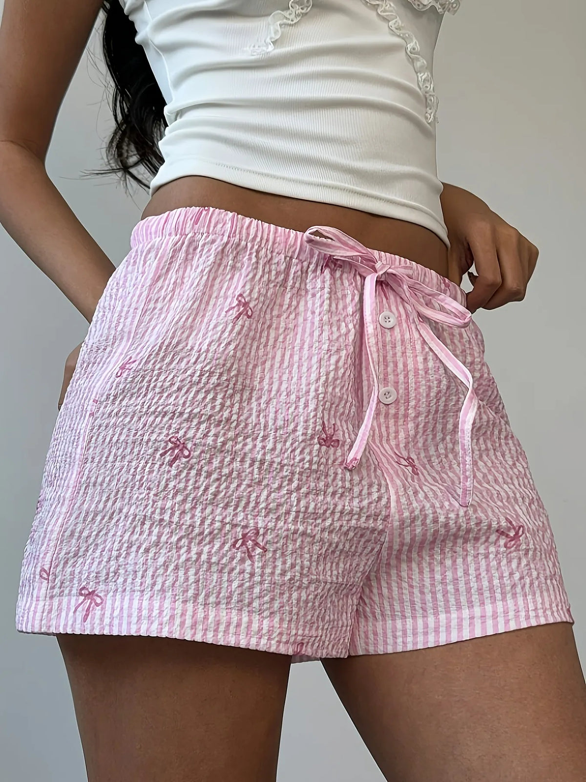 Pink plaid drawstring shorts with bow details, front close-up
