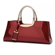 Burgundy patent-look handbag with braided top handles and hanging tag