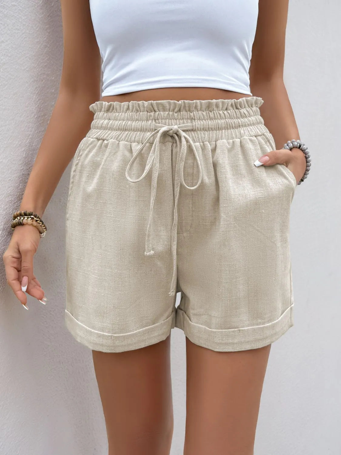 Front view of cream frill-hem shorts with drawstring waist and pockets