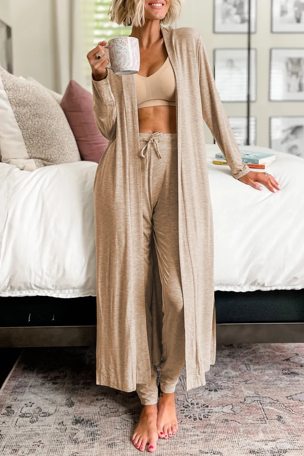 Model wearing tan open-front cardigan and matching pants beside a white sofa