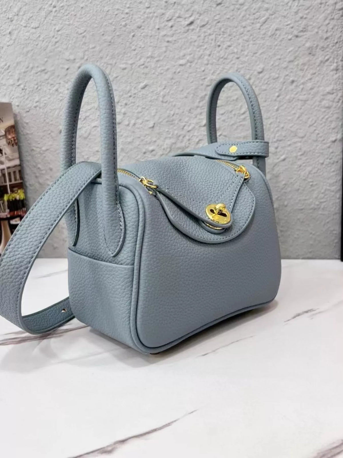 Gray pebbled crossbody bag with gold-tone hardware, front and side view