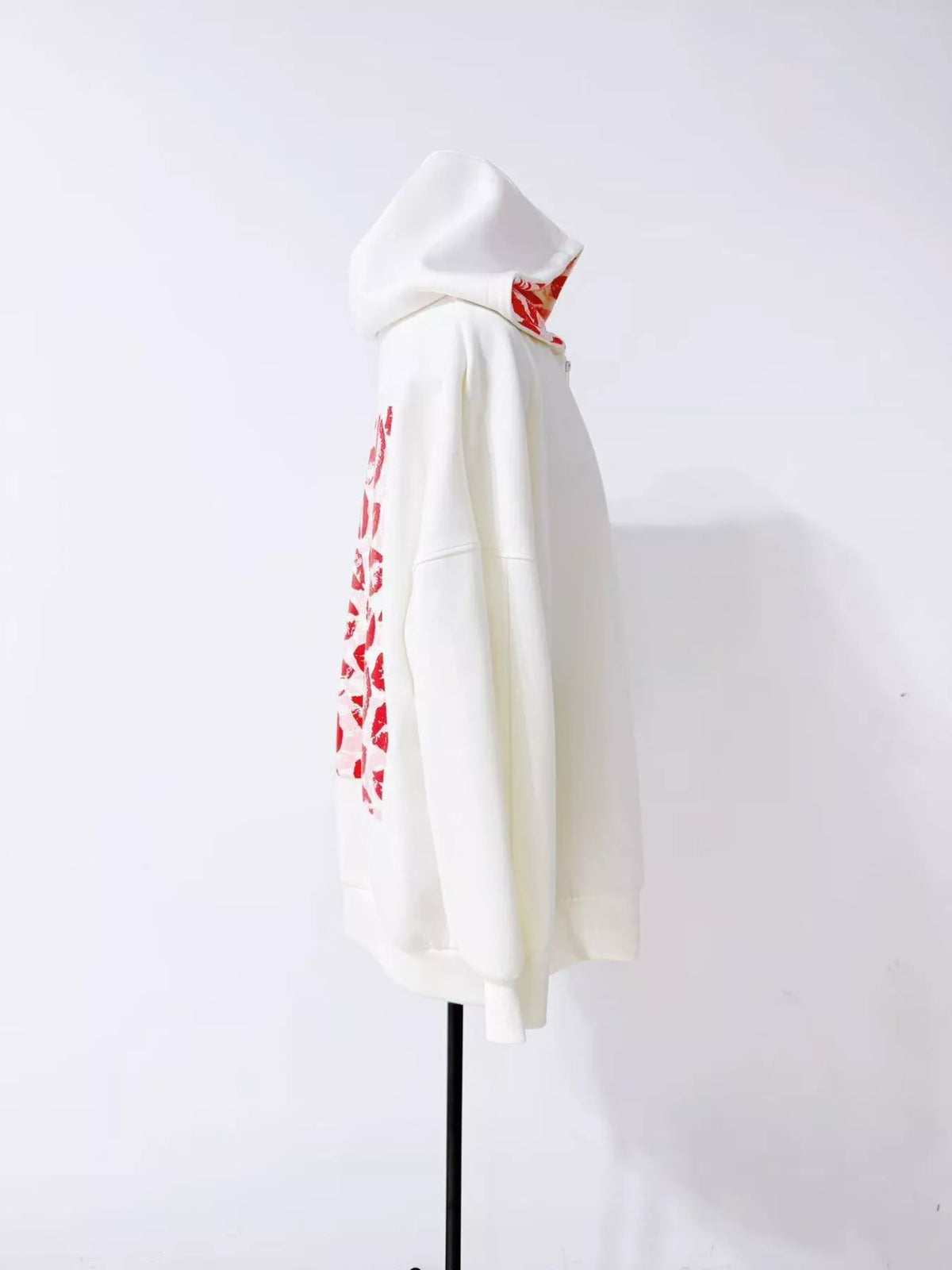 Side view of white zip hoodie on display with the back print partly visible