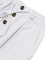 Close-up of white pants showing drawstring, three buttons and pocket