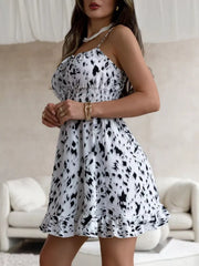 Front view of the white and black abstract-print mini dress showing its fitted bodice and ruffle hem.
