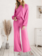 Model wearing pink long-sleeve lounge top and matching drawstring pants, front view