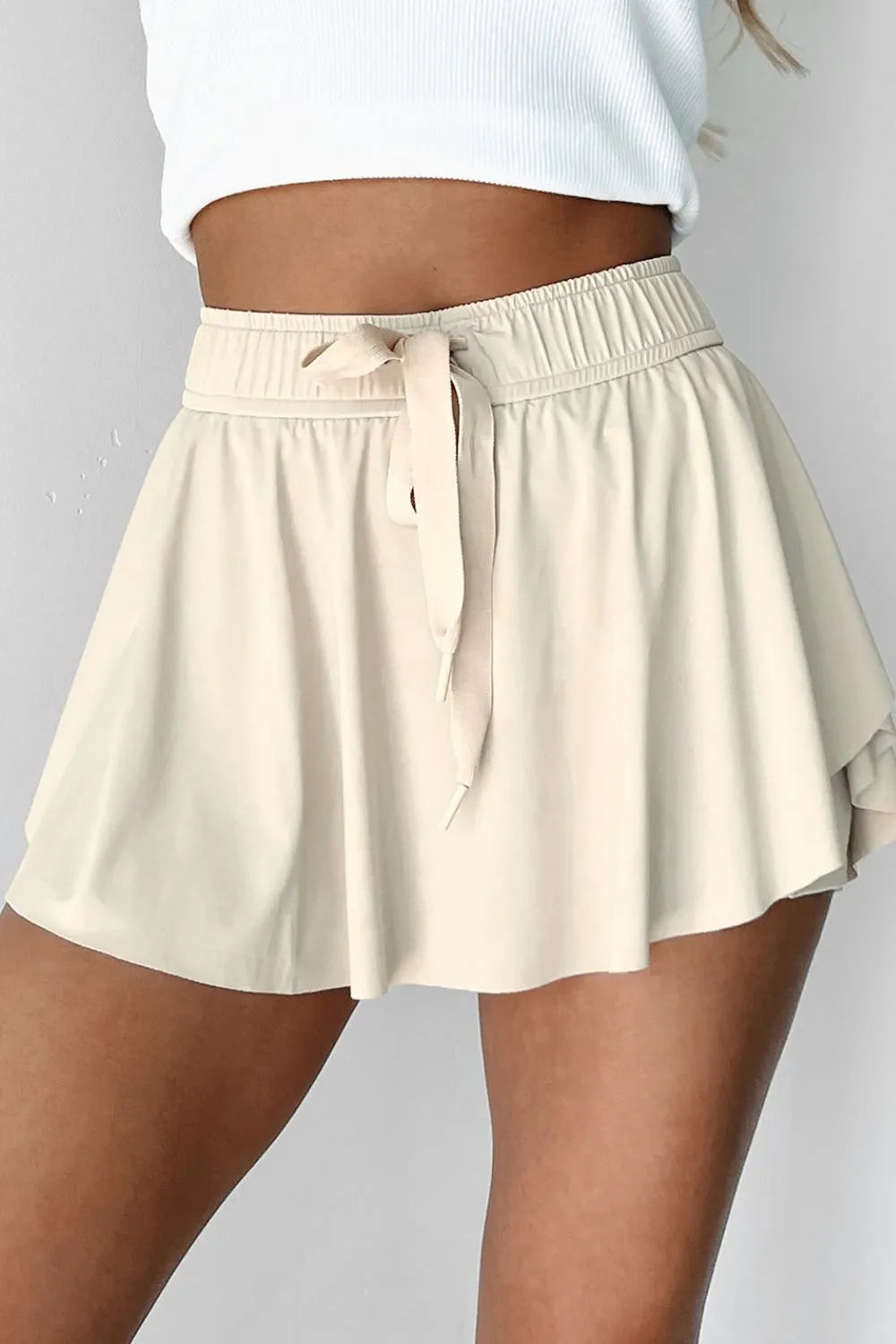 Front view of ivory skort showing the wide ruched waistband and long tie.