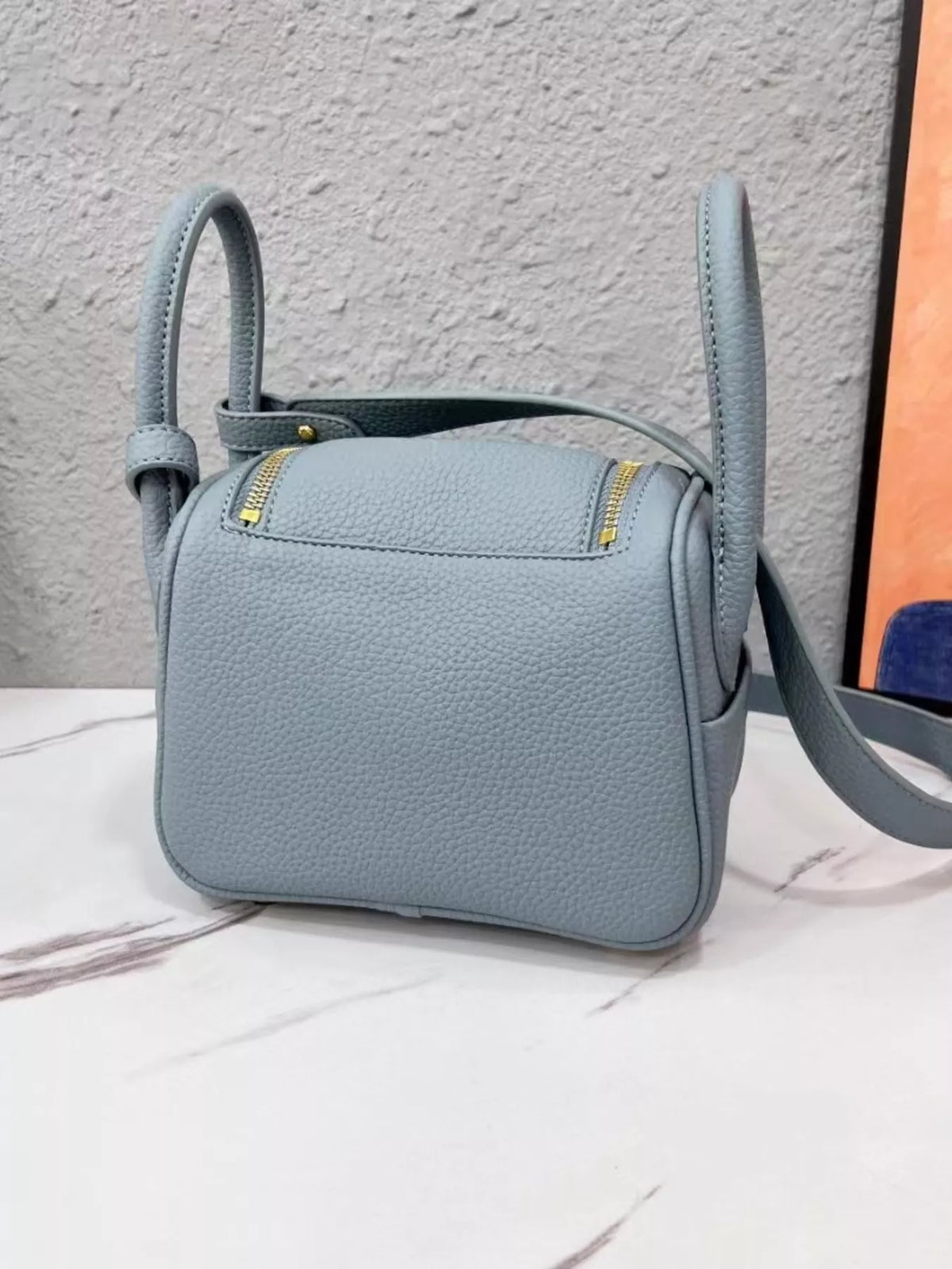 Back view of a blue crossbody bag with two zip pockets