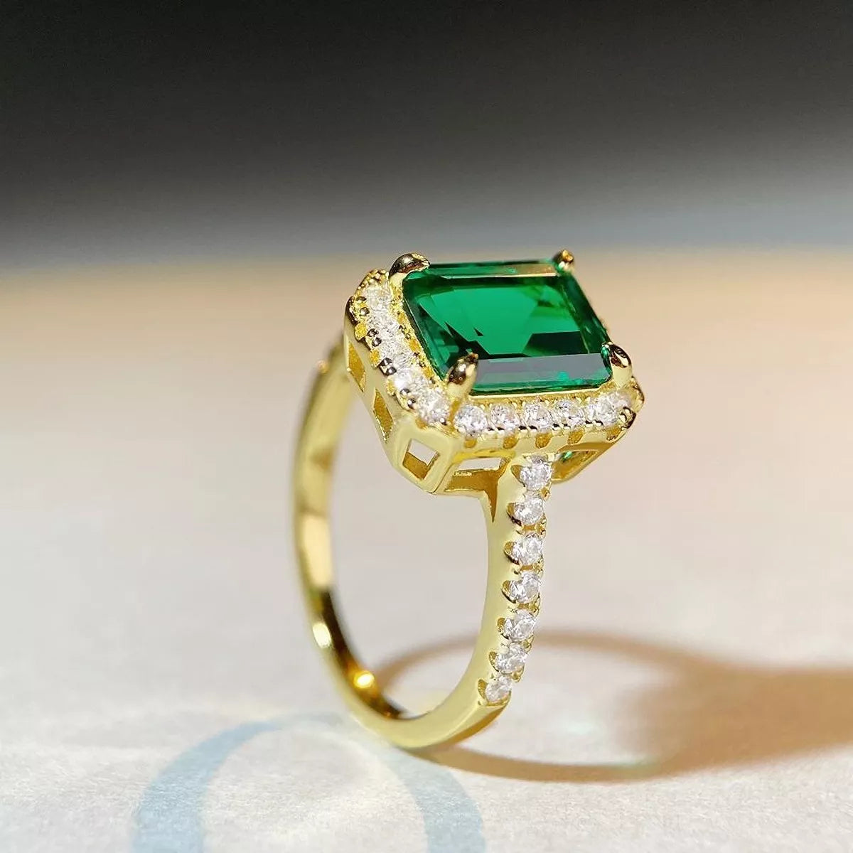 Top view of the rectangular green gemstone-style center and bright halo.