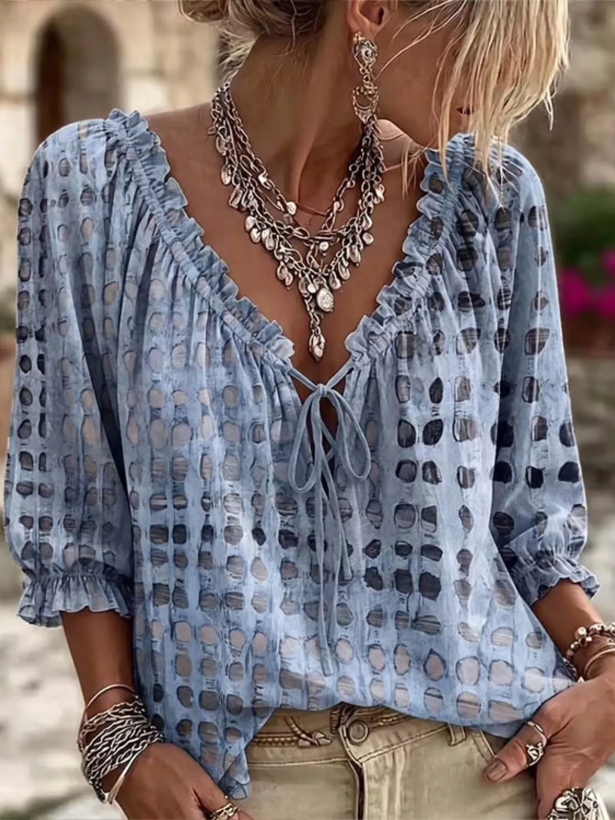 Model wearing the blouse in blue with dark spots and ruffled tie neckline