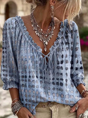 Model wearing the blouse in blue with dark spots and ruffled tie neckline
