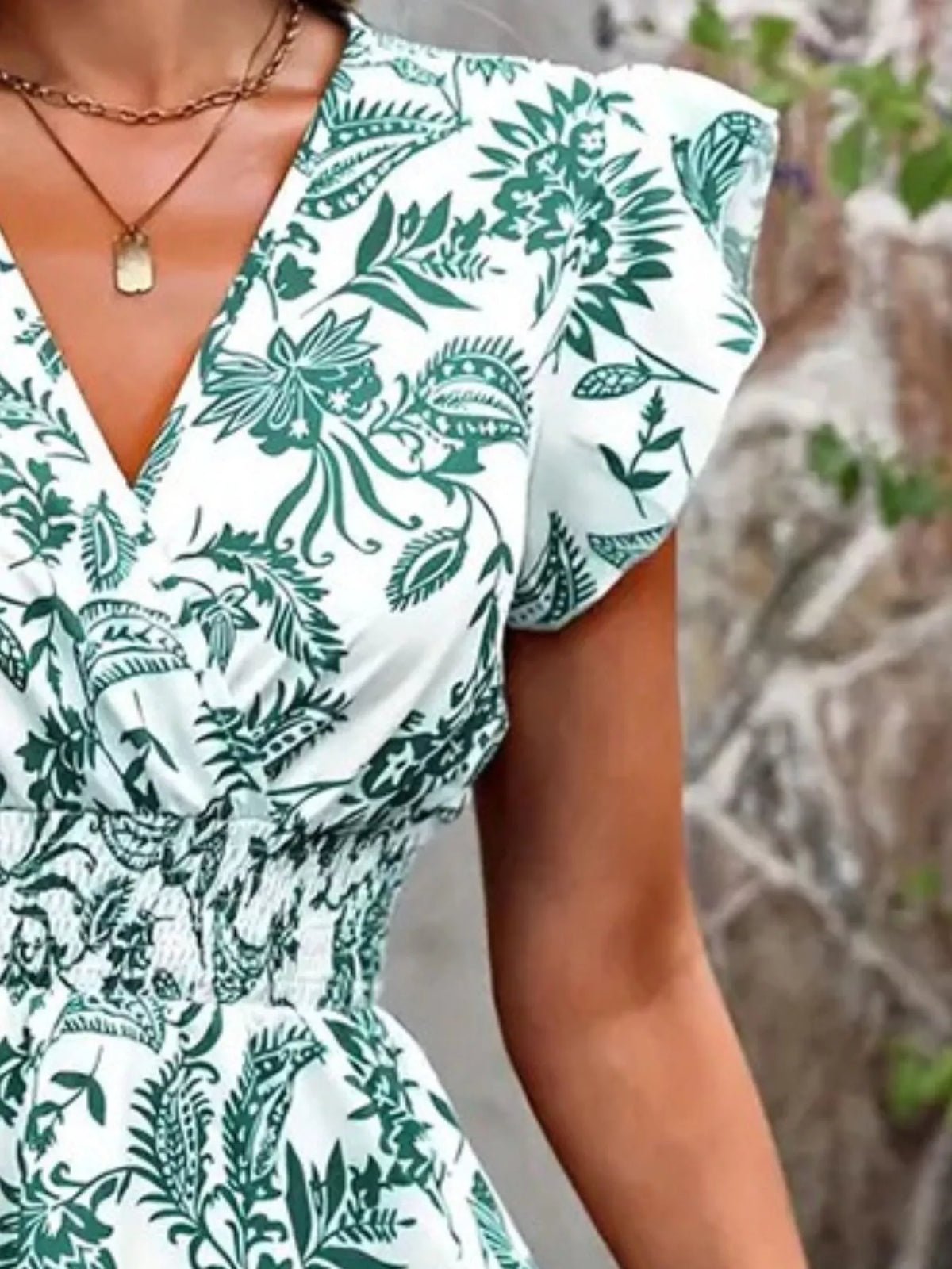 Close-up of green floral fabric, ruffle sleeve and smocked waist