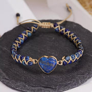 Front view of a blue heart bracelet with navy beads and gold-tone woven details on slate.