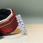Silver zircon band with a row of clear round stones beside its open case.