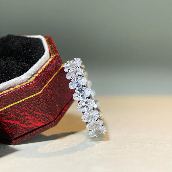 Silver zircon band with a row of clear round stones beside its open case.