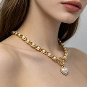 Angled view of pearl chain and heart pendant worn at the neck