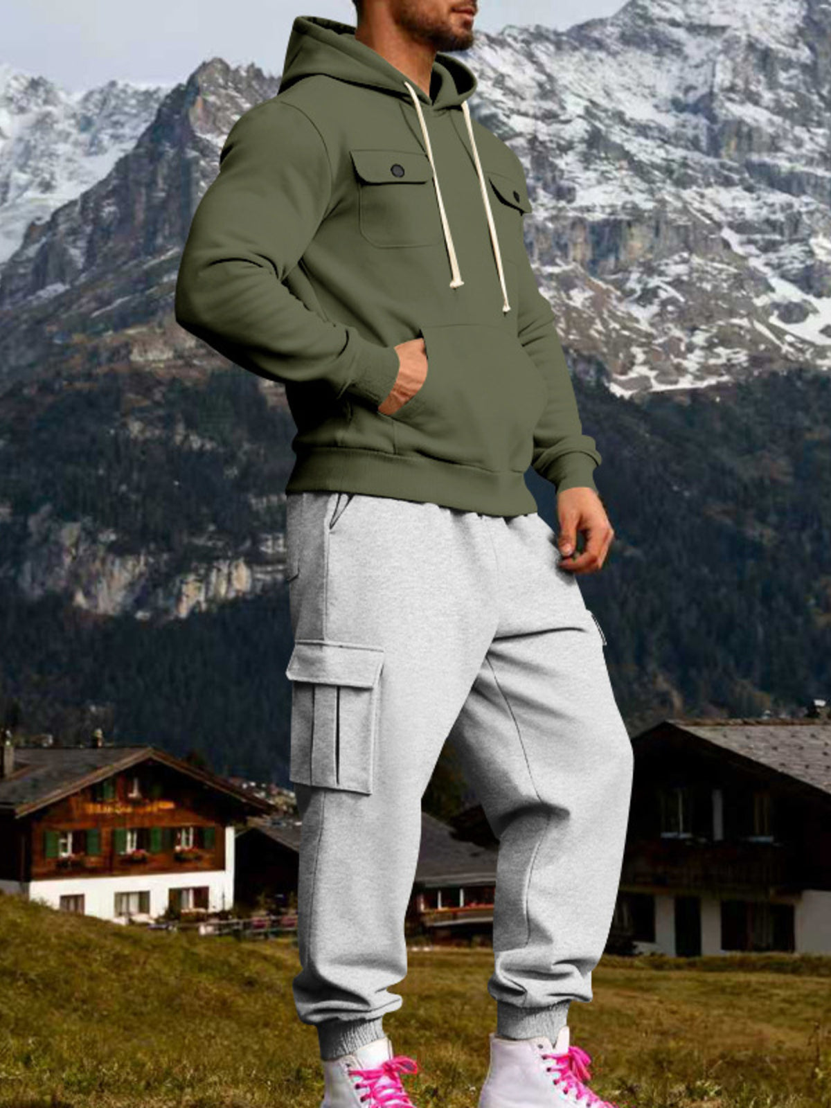 Angled view of olive hoodie and grey cargo joggers with a hand in the kangaroo pocket