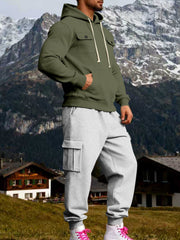 Angled view of olive hoodie and grey cargo joggers with a hand in the kangaroo pocket