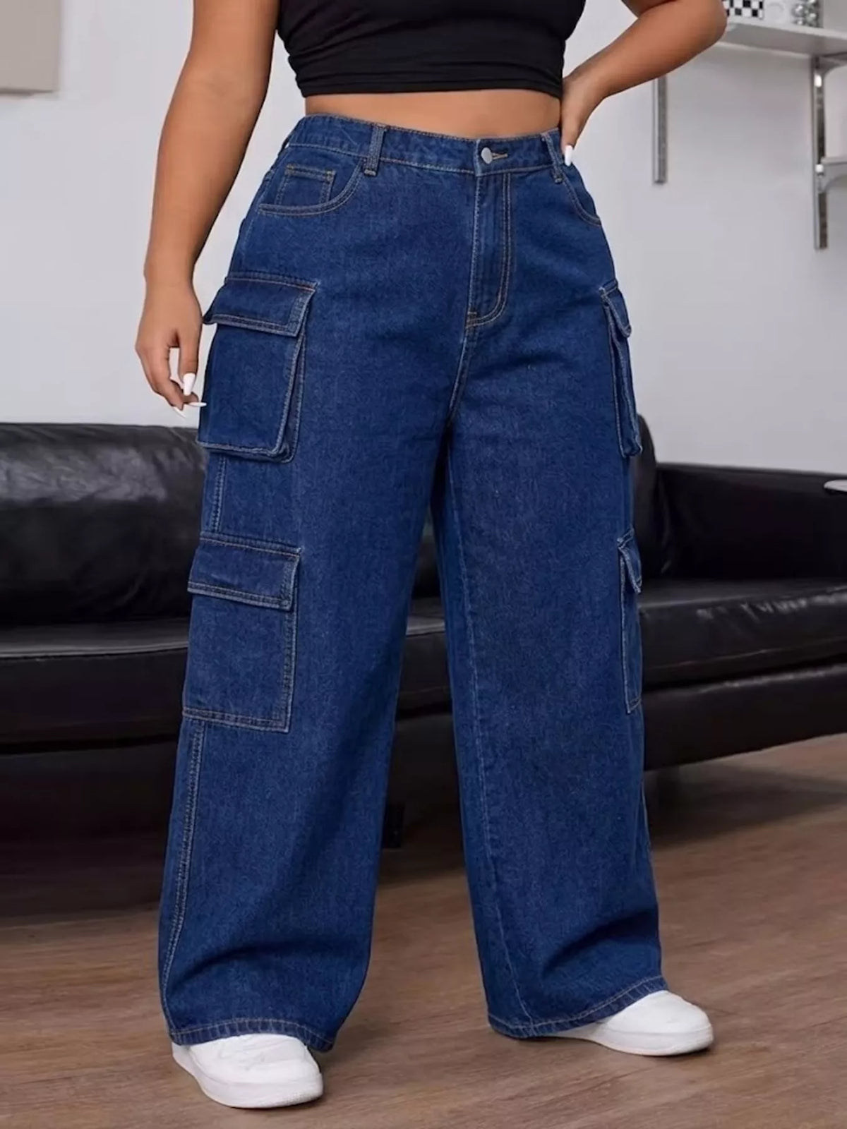 Angled view of dark blue cargo jeans showing stacked flap pockets along the outer leg.