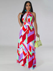 Model in a red and pink geometric halter dress holding a light green handbag at her side.