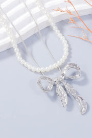White beaded necklace with a silver-tone bow pendant and dangling details