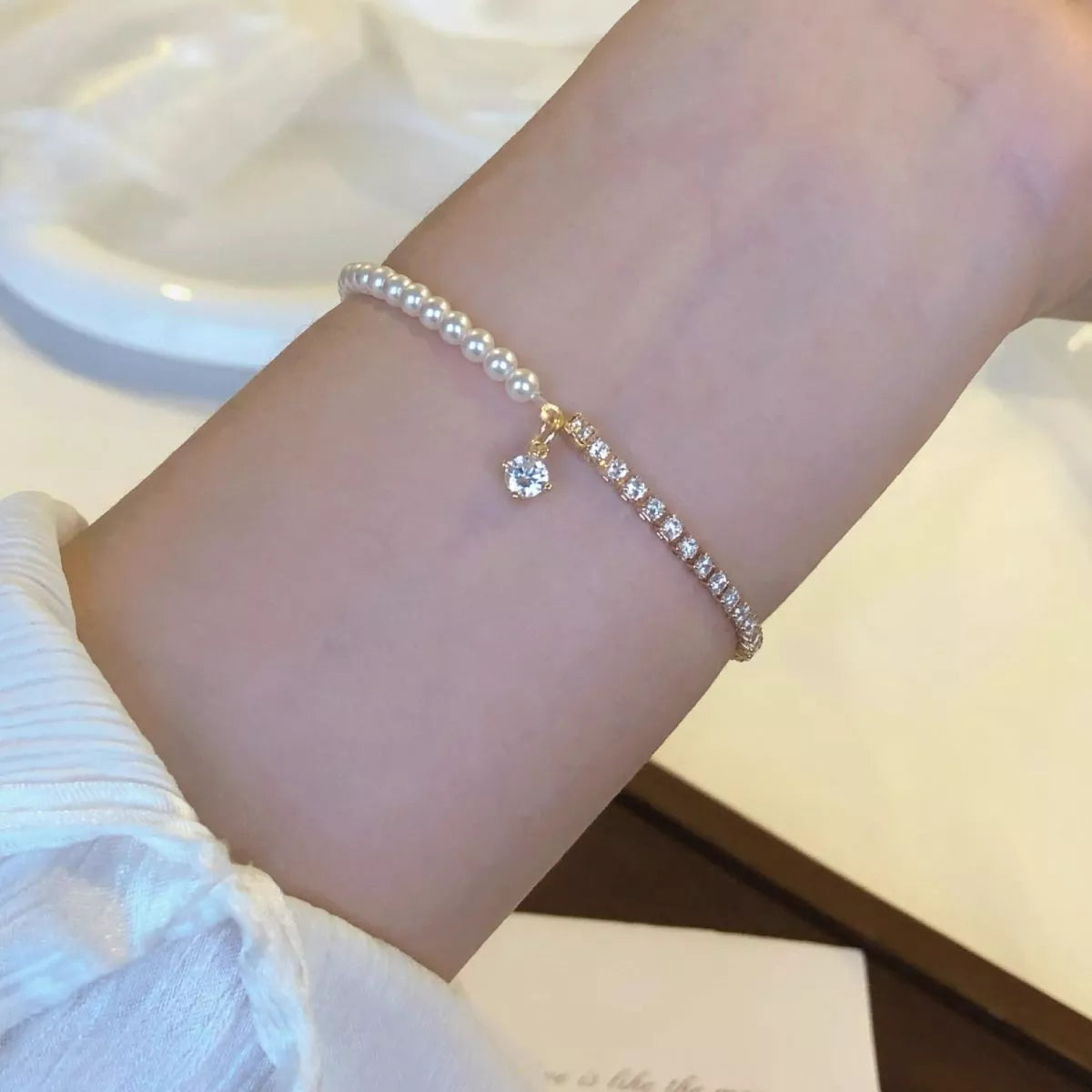 Fine pearl bracelet with a small dangling zircon accent worn on wrist