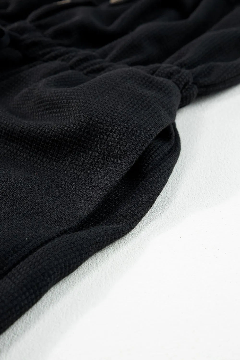 Close-up of gathered textured fabric on black jumpsuit