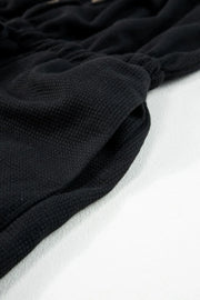 Close-up of gathered textured fabric on black jumpsuit