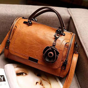 Tan flap bag with flower ornament viewed from above at an angle
