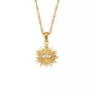 Close-up of gold-tone sunburst pendant and chain on satin