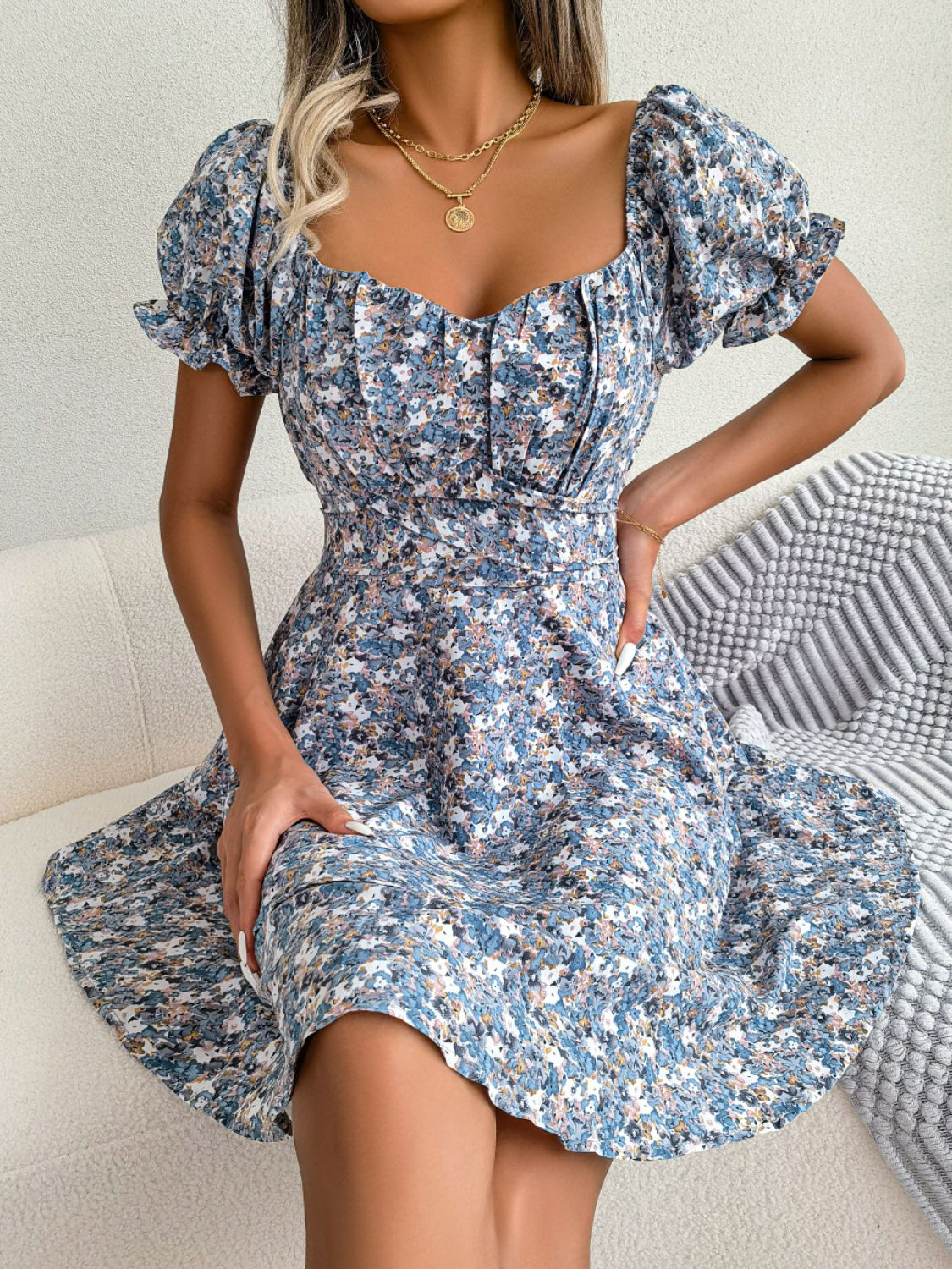 Model seated in blue floral sweetheart-neck dress with flounce sleeves