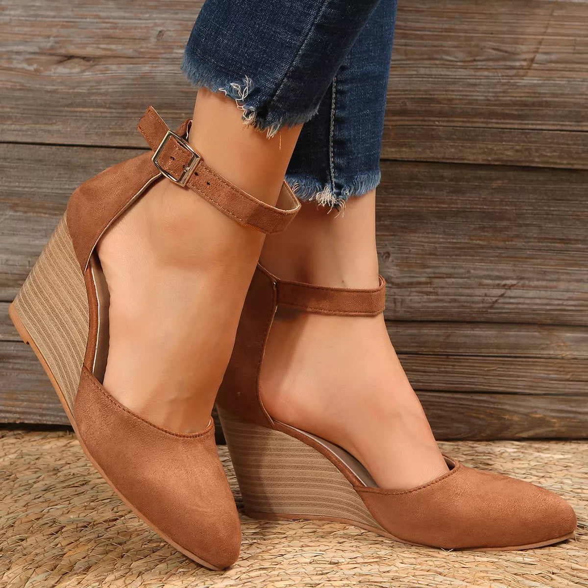 Tan pointed-toe sandals worn from a rear side angle showing wedge heels